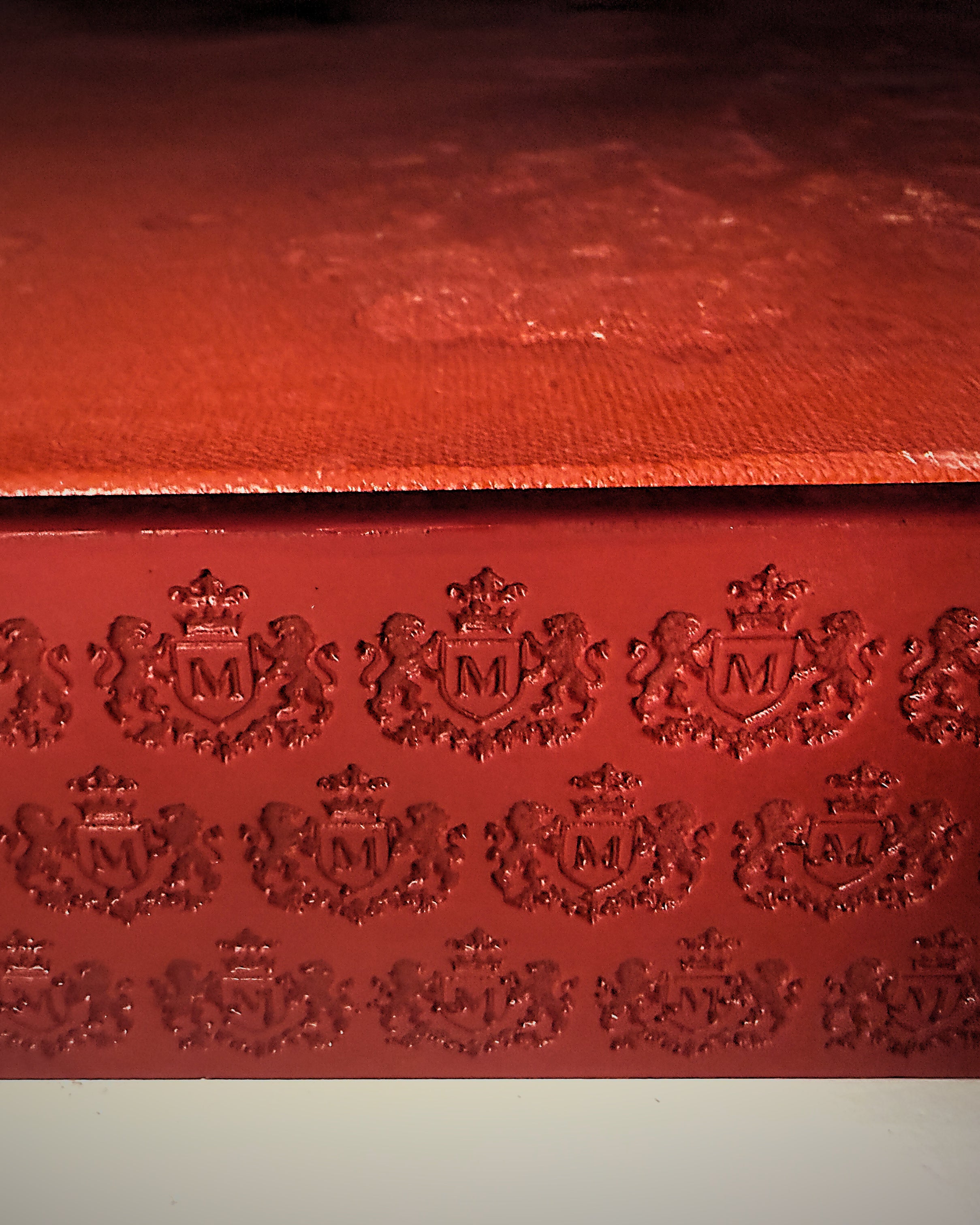 Macro of the House of Moen crest hand-embossed into the red frame face